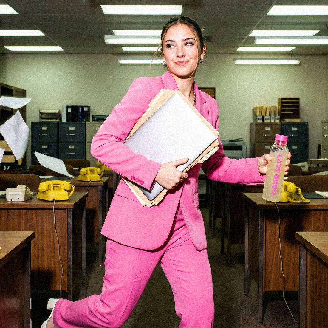 Woman in a pink suit running through an office with a Good Salt bottle